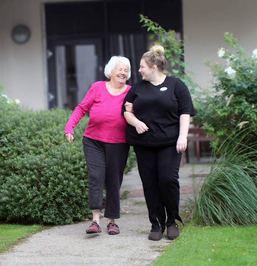 Asset - Belong Morris Feinmann - Lady in Pink walking in the garden with carer